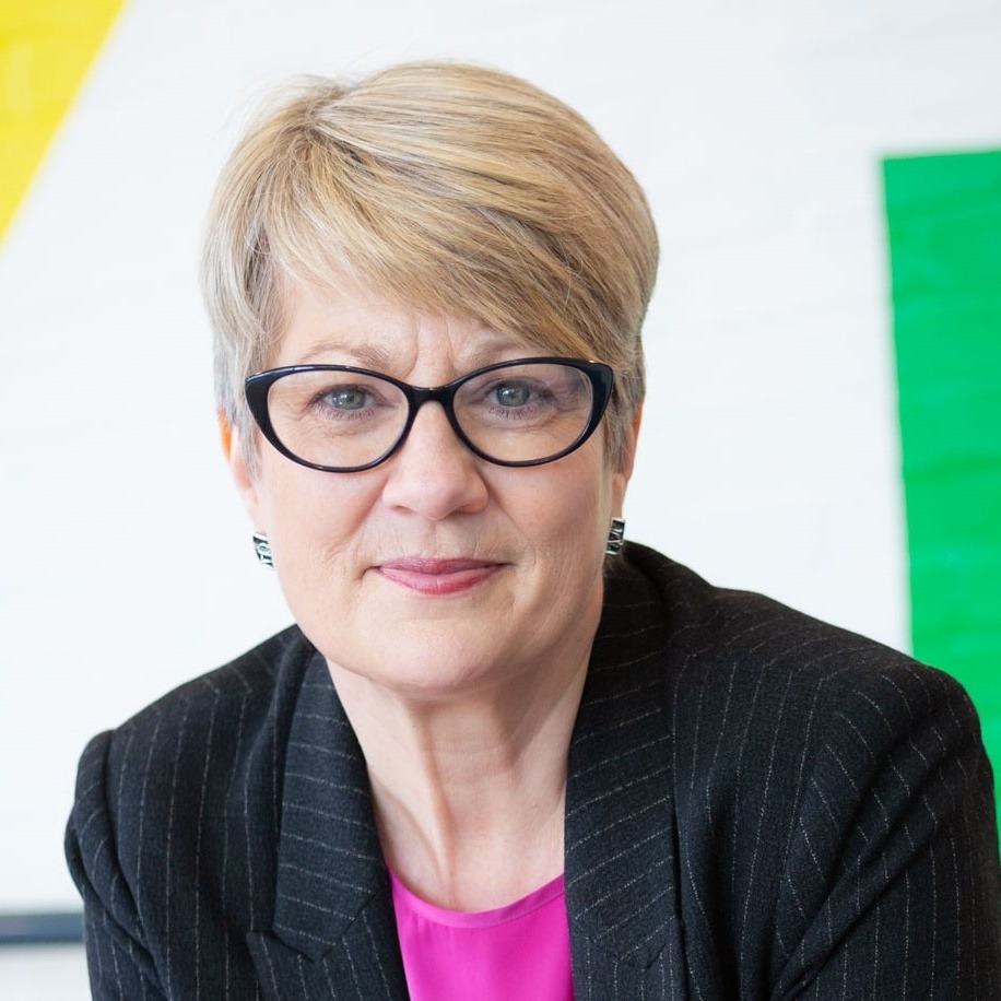 Headshot of Tracey Childs - a white woman with short blonde hair and black glasses.